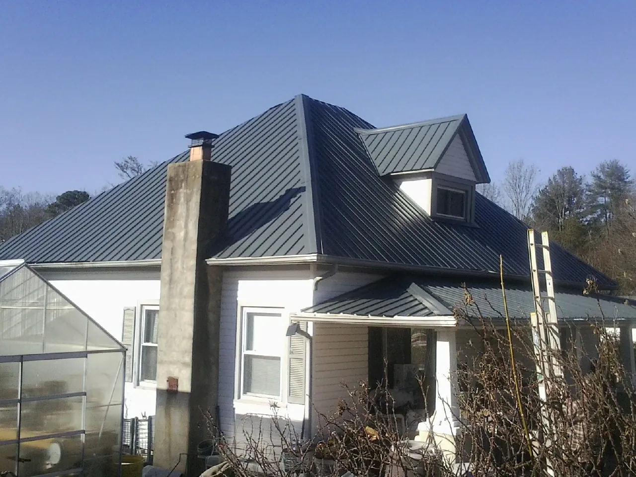 Dark blue standing seam metal roof on a white farmhouse with dormer — Slate & Tile Roof Repair by Roofing Brothers in Slatersville