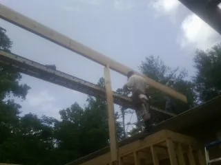Carpenter setting a ridge beam over a new addition frame — Ice Dam Removal by Roofing Brothers in Slatersville