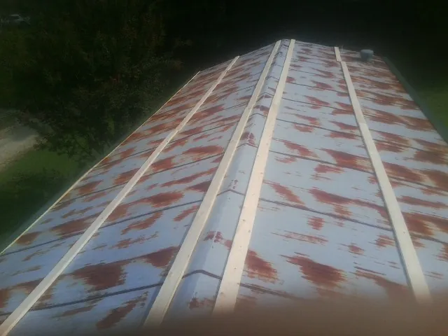 Rusted metal roof panels with new wood purlins before replacement — Storm Damage Roof Repair in Slatersville by Roofing Brothers