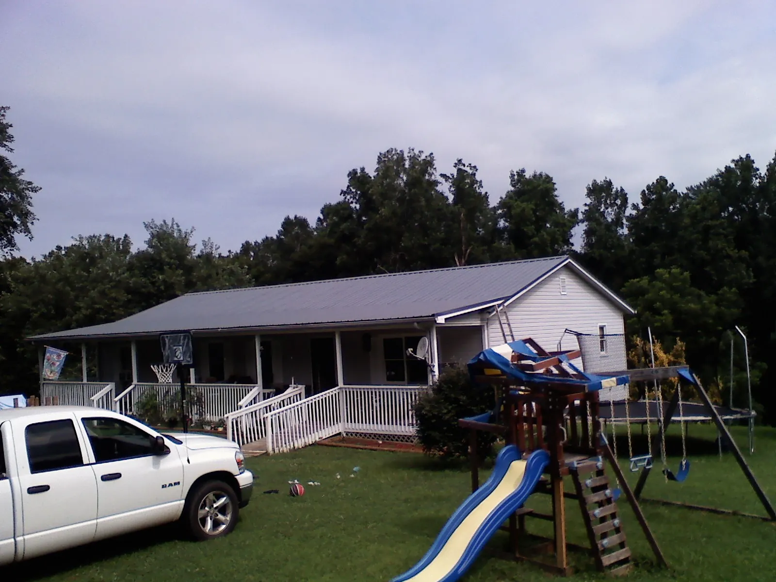 Dark metal roof on a country home with a full length front porch in Slatersville