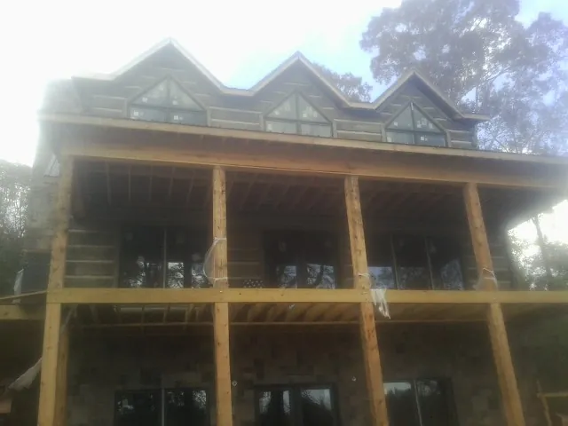 Dormers and porch framing on a large log home under construction — Roof Coating work by our crew in Slatersville