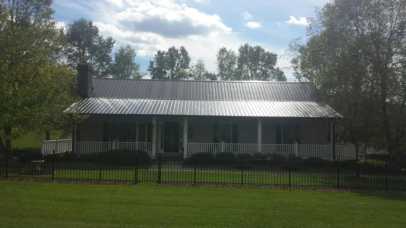 Gray metal roof on a brick ranch with a full width front porch — Gutter Guard Installation work by our crew in Slatersville