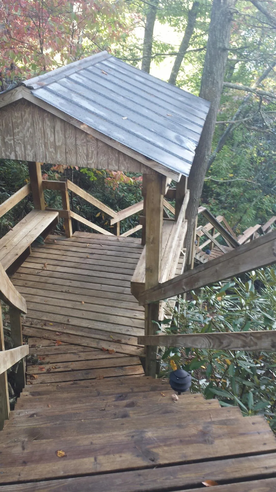 Metal roofed shelter over wooden steps on a wooded walkway — Skylight Repair & Installation work by our crew in Slatersville