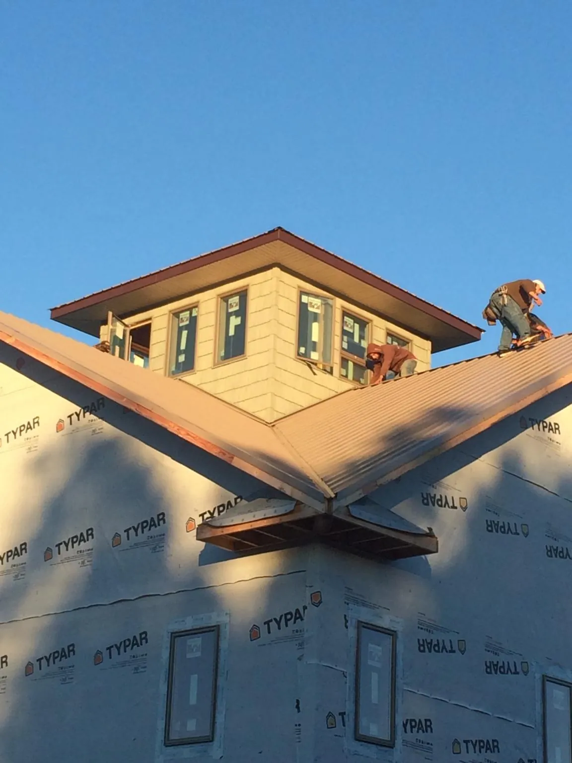 Roofers working around a rooftop cupola on a new metal roof at sunset — Roof Waterproofing in Slatersville by Roofing Brothers